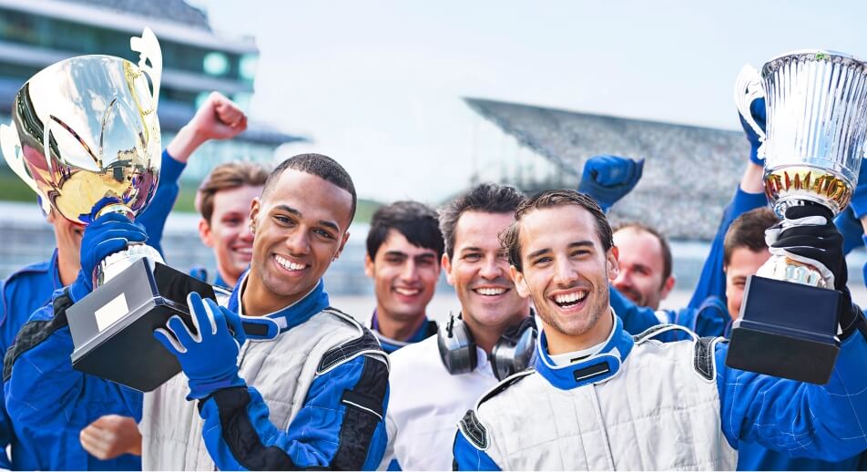 Group of smiling race car drivers holding trophies