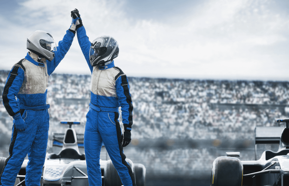 Two race car drivers in blue and white suits high-fiving